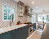 Kitchen with double oven range, hanging light fixtures, a healthy amount of sunlight, and exhaust hood