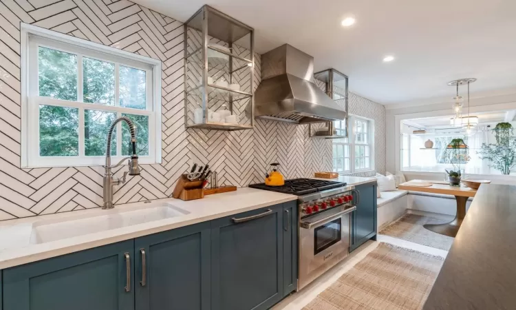 Kitchen with double oven range, hanging light fixtures, a healthy amount of sunlight, and exhaust hood