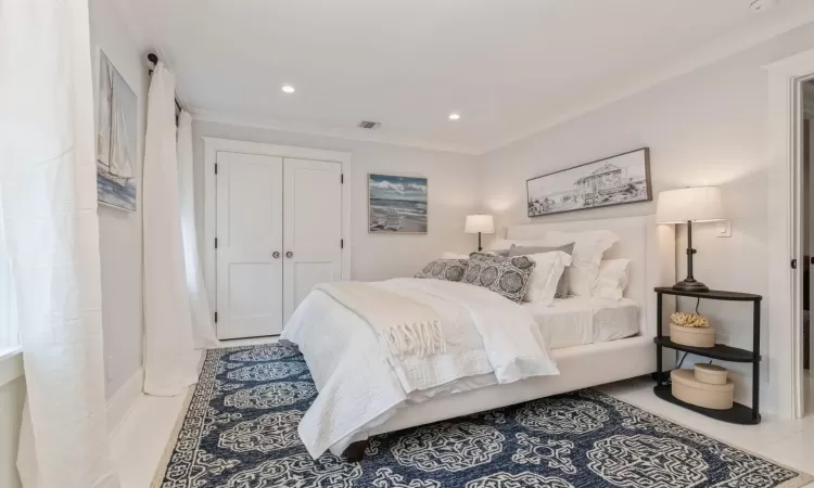 Tiled bedroom with ornamental molding and a closet