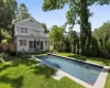 Rear view of property featuring a fenced in pool, a balcony, and a lawn