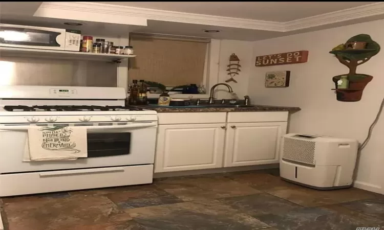 Kitchen featuring white cabinets, white appliances, ornamental molding, and sink