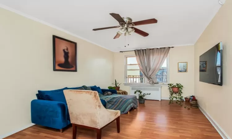 Sitting room with radiator heating unit, hardwood / wood-style flooring, and ornamental molding