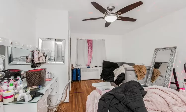 Bedroom with radiator, ceiling fan, and dark hardwood / wood-style floors