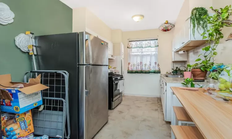 Kitchen with stainless steel appliances, white cabinetry, and sink