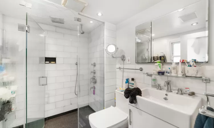 Bathroom with a shower with door, vanity, and toilet