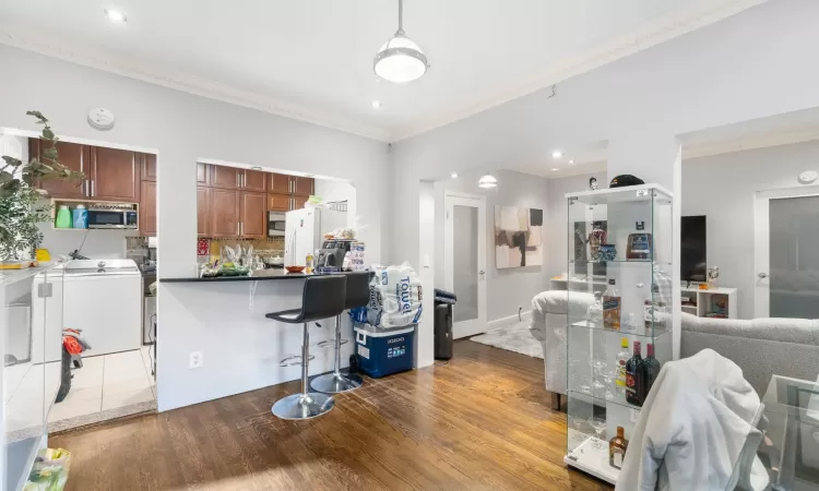 Kitchen with white fridge, ornamental molding, dark wood-type flooring, and tasteful backsplash