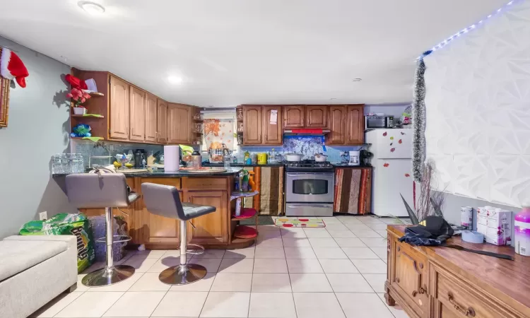 Kitchen with backsplash, light tile patterned flooring, and stainless steel appliances