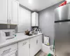 Kitchen featuring stainless steel refrigerator, white cabinetry, sink, and light hardwood / wood-style floors