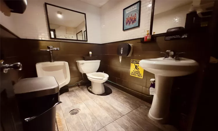 Bathroom with hardwood / wood-style floors, toilet, and tile walls