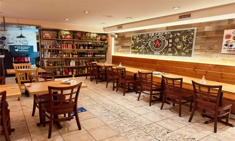 Tiled dining space featuring wood walls and bar area