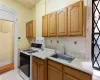 Kitchen featuring light tile patterned flooring, white gas range oven, tasteful backsplash, and sink