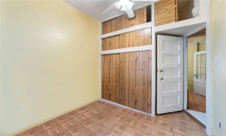 Spare room with ceiling fan, wood walls, and parquet floors