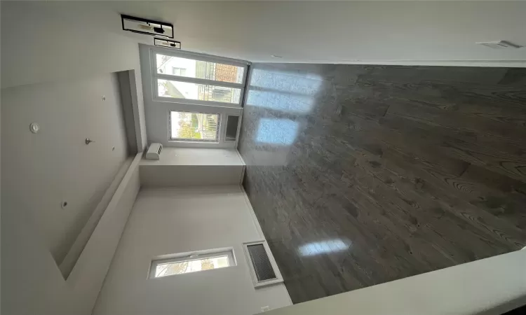 Empty room with dark hardwood / wood-style floors, a wall mounted AC, a wealth of natural light, and a tray ceiling