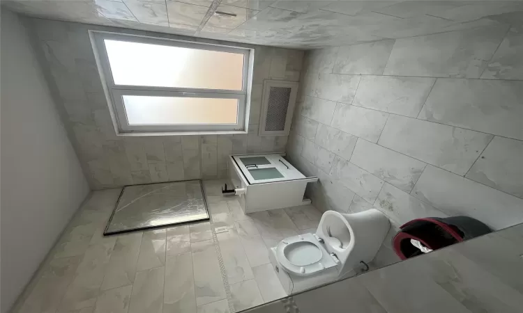 Bathroom featuring vanity, tile walls, and toilet