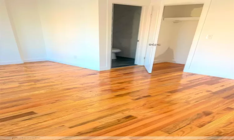 Unfurnished bedroom featuring ensuite bathroom, light hardwood / wood-style flooring, and a closet