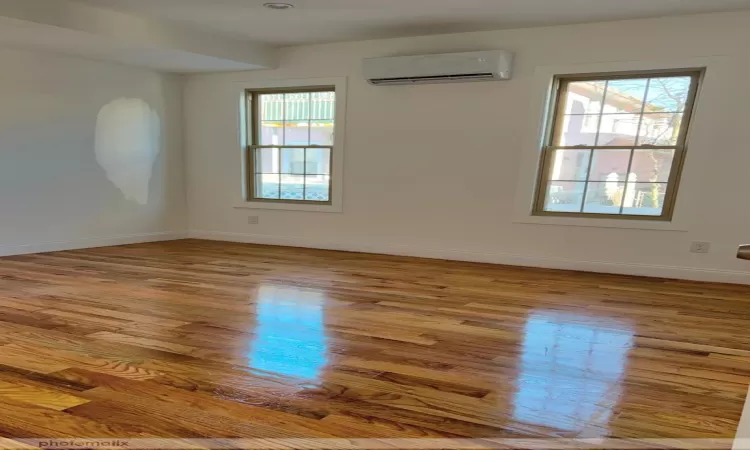 Empty room featuring light hardwood / wood-style flooring and a wall mounted air conditioner