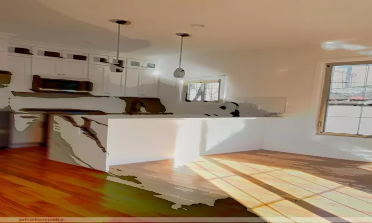 Kitchen featuring pendant lighting, a healthy amount of sunlight, white cabinetry, and light hardwood / wood-style flooring