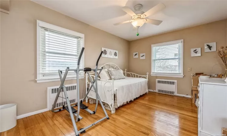 Bedroom featuring radiator, ceiling fan, and multiple windows