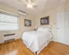 Bedroom with a wall mounted air conditioner, ceiling fan, radiator heating unit, and light hardwood / wood-style flooring