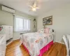 Bedroom with an AC wall unit, radiator, ceiling fan, and hardwood / wood-style floors