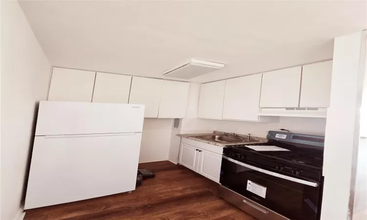 Kitchen featuring white cabinetry, stainless steel range, sink, dark wood-type flooring, and white refrigerator