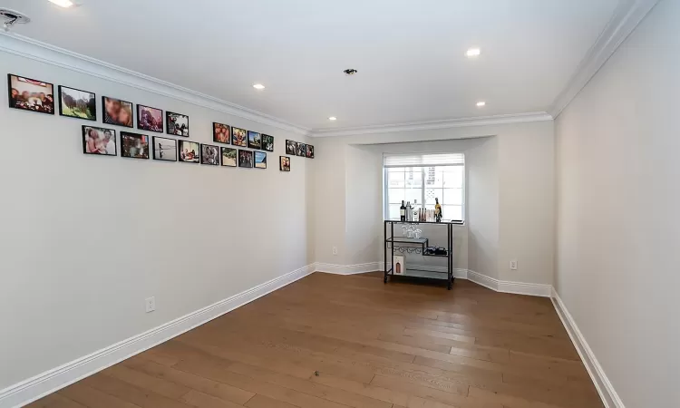 Spare room featuring crown molding and dark wood-type flooring