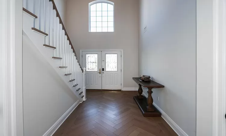 Entrance foyer featuring french doors, dark parquet flooring, and a healthy amount of sunlight