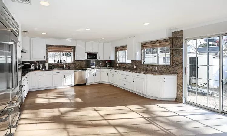 Kitchen featuring stainless steel dishwasher, white cabinetry, black microwave, and tasteful backsplash