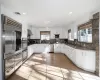 Kitchen with white cabinets, stainless steel appliances, light hardwood / wood-style flooring, and range hood