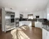 Kitchen with built in appliances, dark hardwood / wood-style floors, white cabinetry, and wall chimney range hood