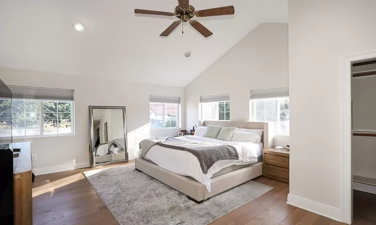 Bedroom featuring multiple windows, high vaulted ceiling, and dark hardwood / wood-style floors