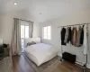 Bedroom featuring dark hardwood / wood-style flooring, lofted ceiling, and multiple windows