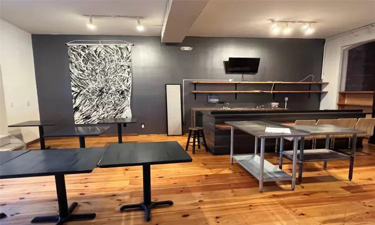 Bar with light hardwood / wood-style floors and track lighting