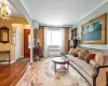 Living room featuring crown molding, wood-type flooring, an inviting chandelier, an AC wall unit, and radiator heating unit