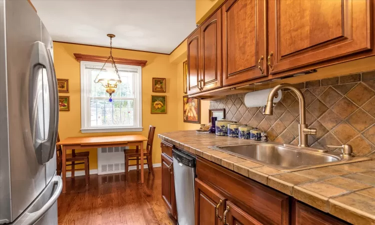 Kitchen with pendant lighting, sink, dark hardwood / wood-style floors, tasteful backsplash, and stainless steel appliances