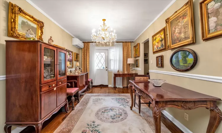 Home office featuring wood-type flooring, an inviting chandelier, an AC wall unit, and ornamental molding