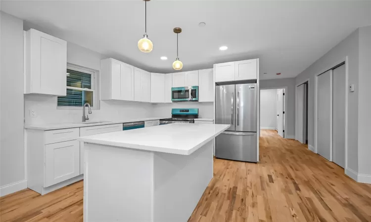 Kitchen with white cabinets, sink, a kitchen island, and appliances with stainless steel finishes