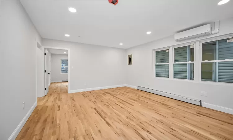 radiator, light hardwood / wood-style flooring, and a wall mounted AC