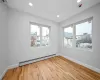 Spare room featuring hardwood / wood-style floors, a wall mounted air conditioner, and a baseboard heating unit