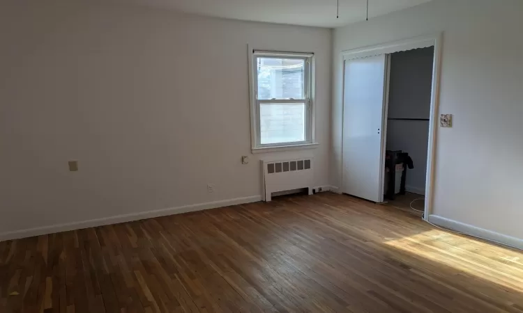 Empty room featuring radiator and dark hardwood / wood-style floors