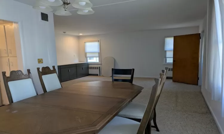 Carpeted dining space with radiator