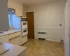 Kitchen featuring white appliances, cream cabinets, sink, light hardwood / wood-style floors, and radiator heating unit