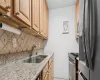 Kitchen with sink, stainless steel appliances, light stone counters, decorative backsplash, and light tile patterned flooring