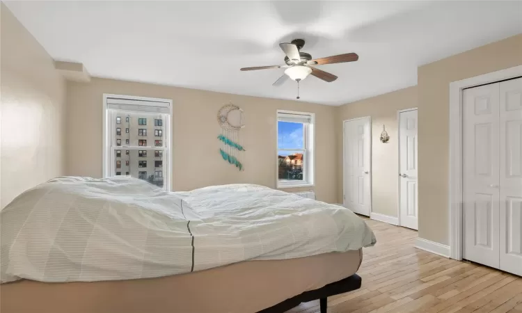 Bedroom with multiple closets, ceiling fan, and light hardwood / wood-style flooring