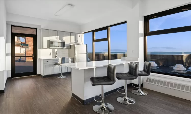 Kitchen with gray cabinetry, stainless steel appliances, tasteful backsplash, kitchen peninsula, and a breakfast bar area