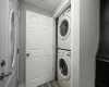 Clothes washing area with dark hardwood / wood-style flooring and stacked washer and dryer