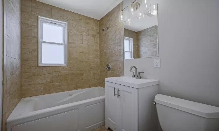 Full bathroom with vanity, tiled shower / bath, and toilet