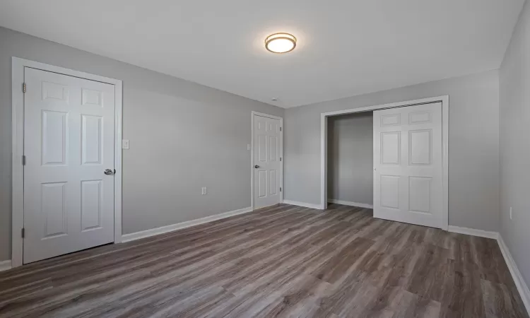 Unfurnished bedroom featuring dark wood-type flooring