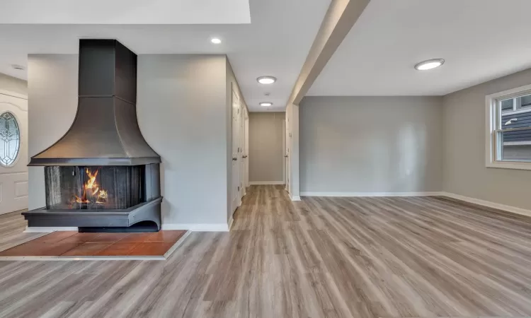 Unfurnished living room with a multi sided fireplace and light hardwood / wood-style floors