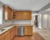 Kitchen with a wood stove, light stone countertops, light hardwood / wood-style flooring, and stainless steel dishwasher